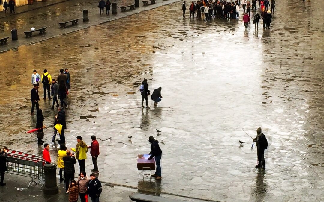 People and pigeons gather on stone ground in the rain